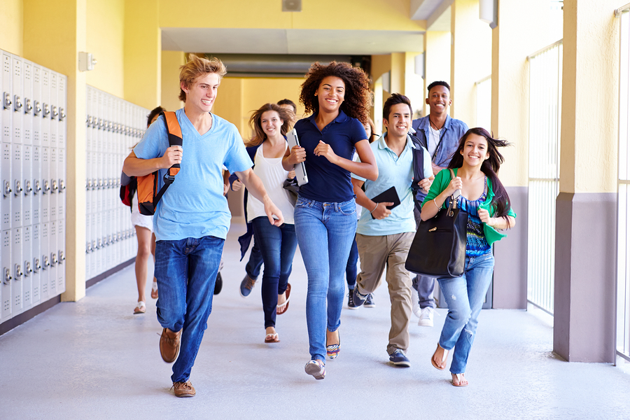 Group Of High School Students Running In Corridor